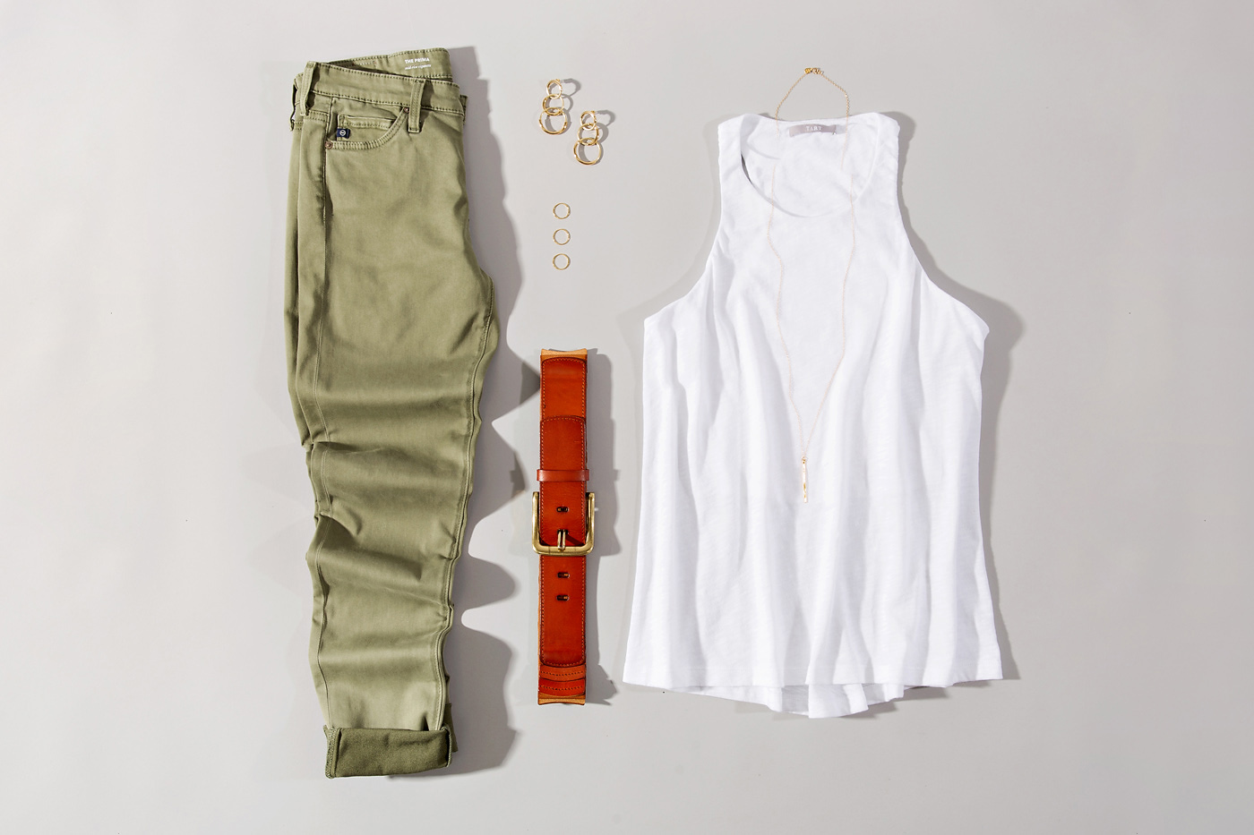 white tank styled with green skinny jeans and simple accessories